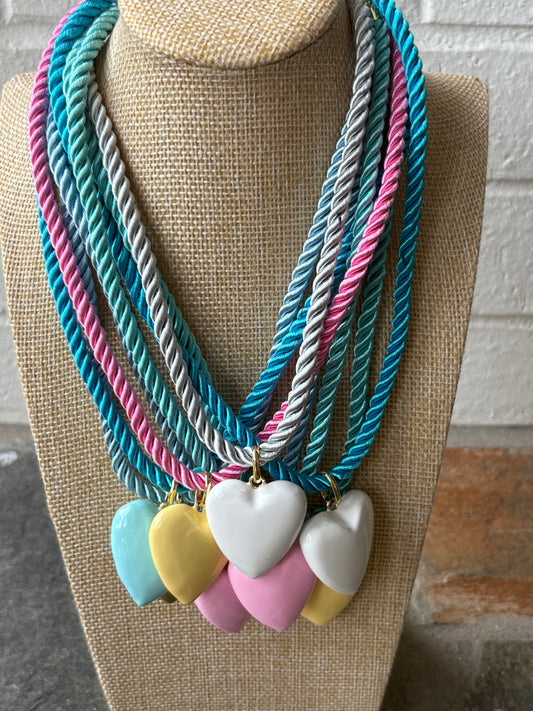 Necklace with colorful heart pendants on a mannequin bust against a textured wall.